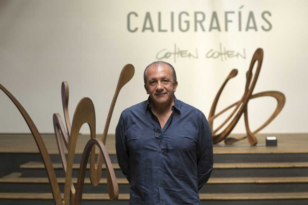 Fotografía de una exposición de escultura contemporánea asociada a la obra de Moisés Cohen Cohen, artista y escultor con trayectoria en el ámbito del arte abstracto. La imagen muestra un espacio expositivo con esculturas de gran formato inspiradas en la caligrafía, realizadas en materiales orgánicos y tonos naturales, que evocan movimiento, gesto y escritura tridimensional. La serie “Caligrafías” dialoga entre arte, materia y lenguaje, reflejando una exploración escultórica profunda vinculada a procesos artesanales y sensibilidad contemporánea.